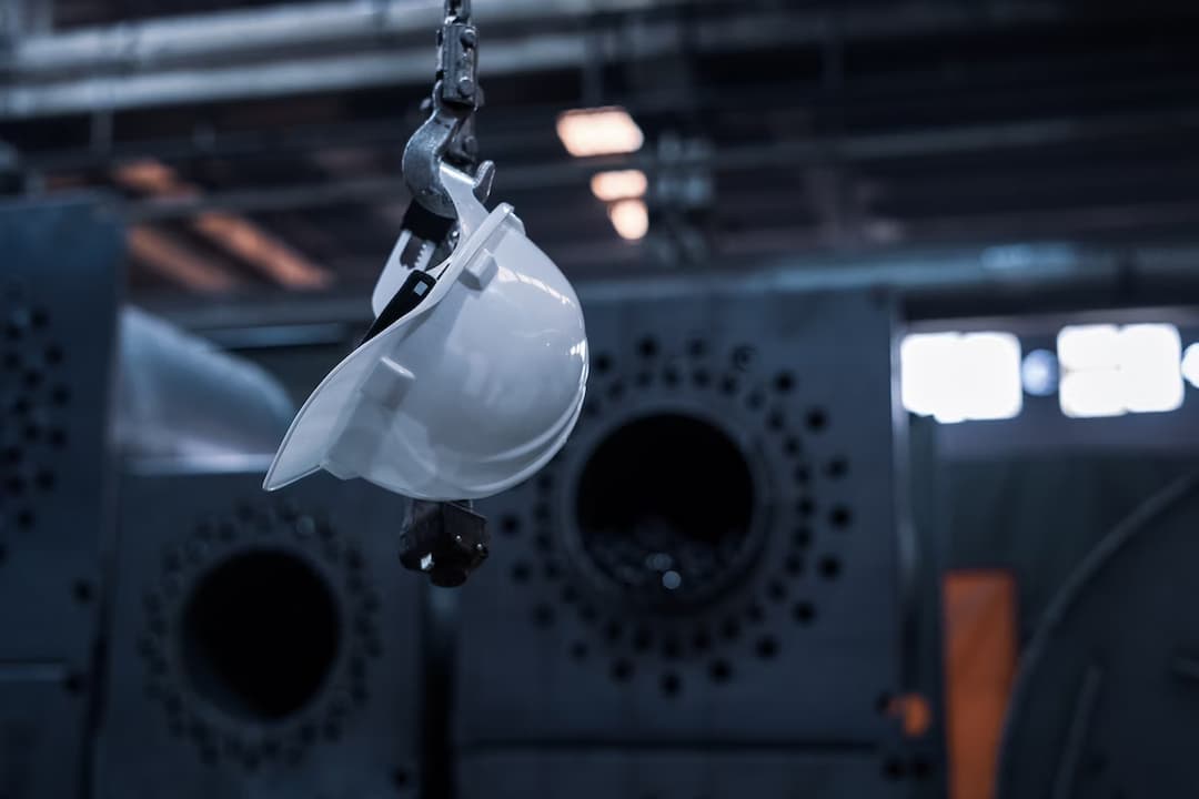 Capacete branco pendurado em gancho de guindaste